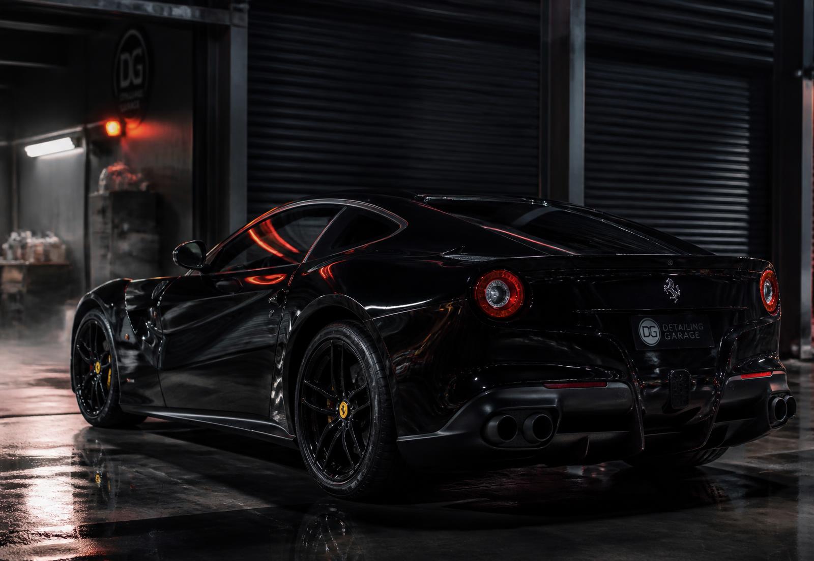 Freshly detailed glossy black sports car in a dark garage